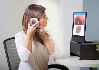 Tytocare Ear Exam - woman holding inspection device into her ear while looking at the output on screen.