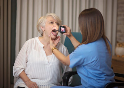 Nurse holding inspection device to a woman's throat.
