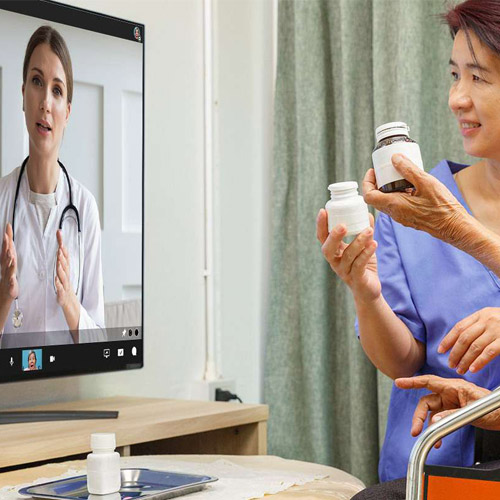 nurse with elderly woman video conference with doctor on monitor