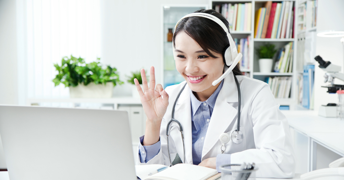 Female doctor doing an OK sign in front of computer